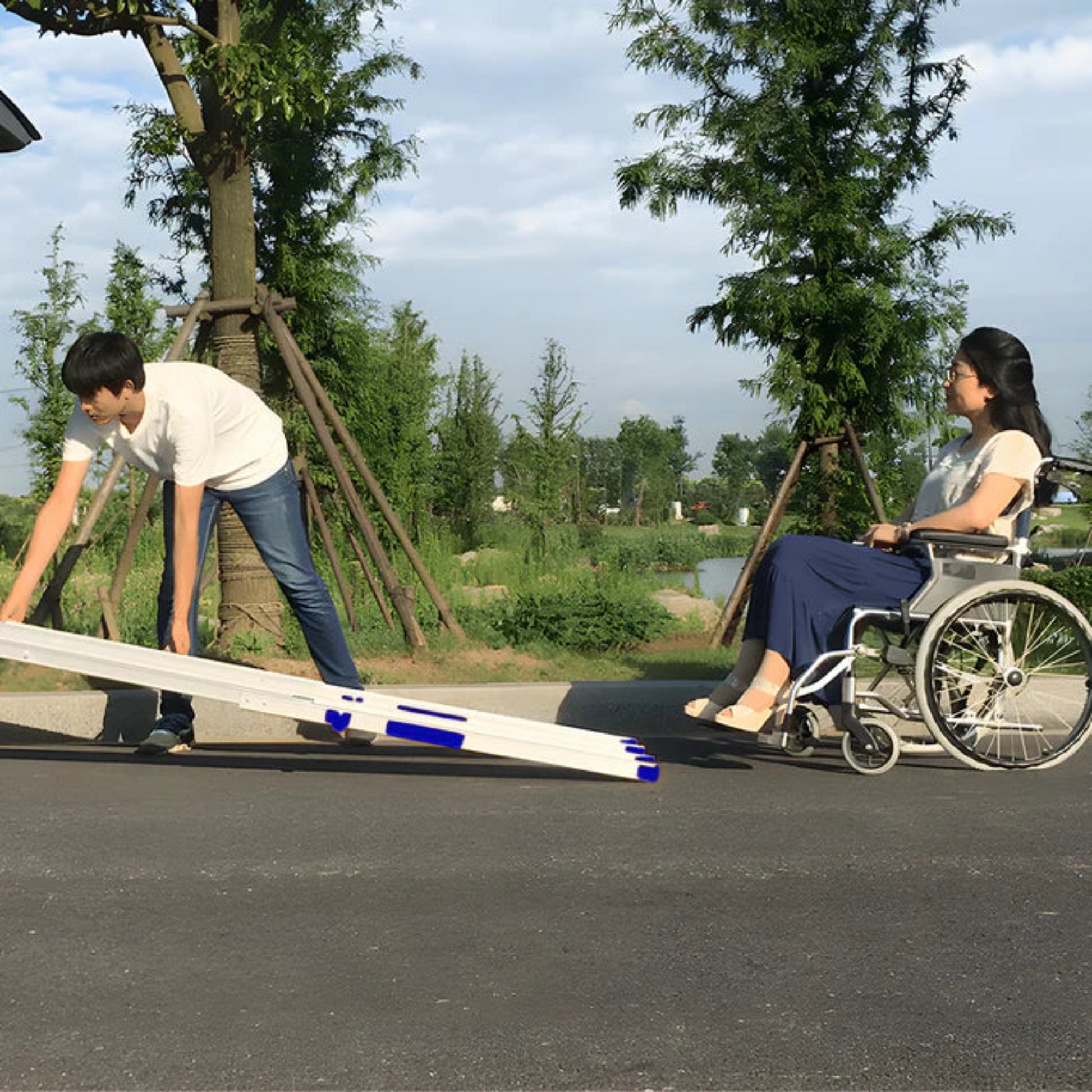 Person in a wheelchair being helped by another person with a heeve telescopic ramp