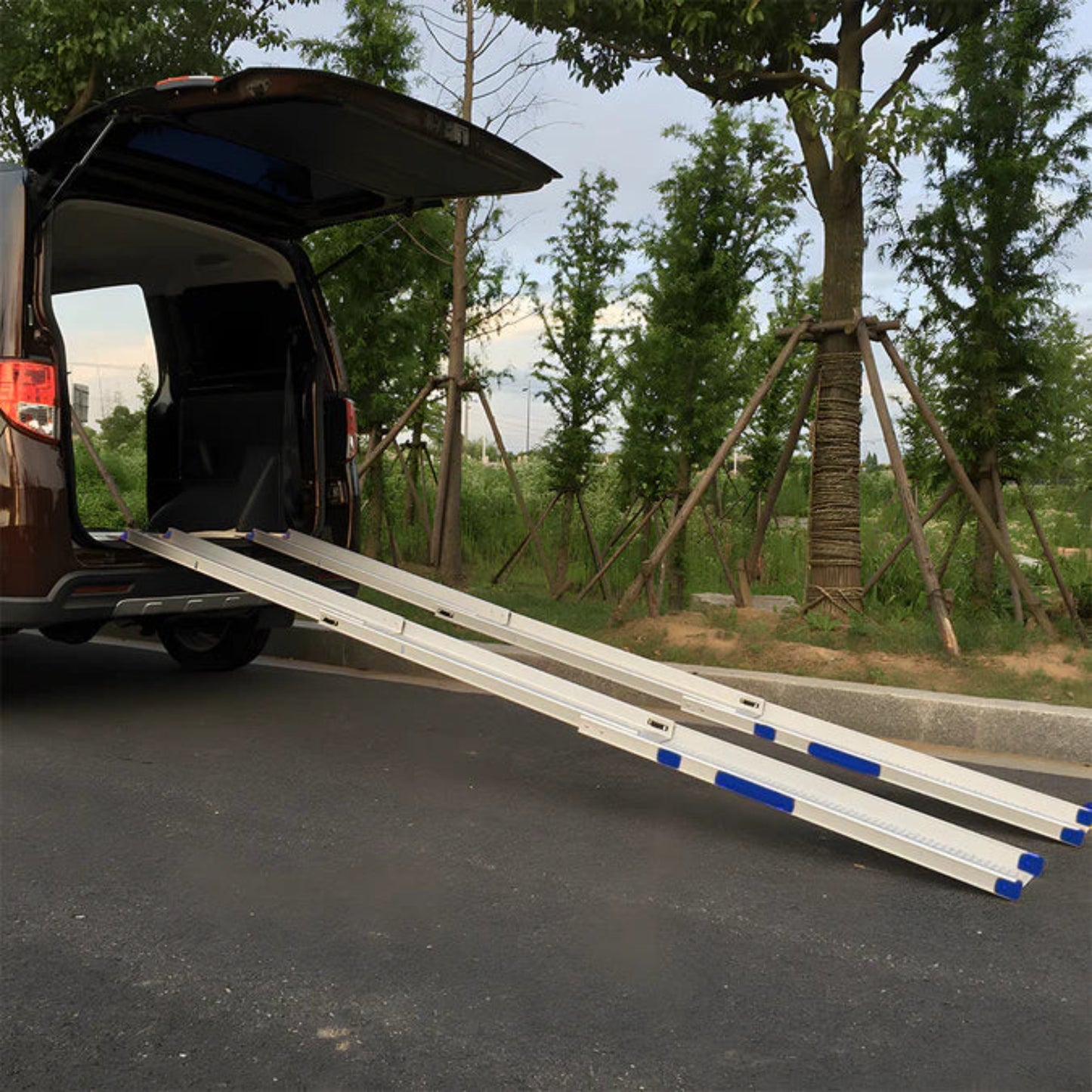 Van with an extended Heeve Telescopic wheelchair ramp on a road with trees in the background