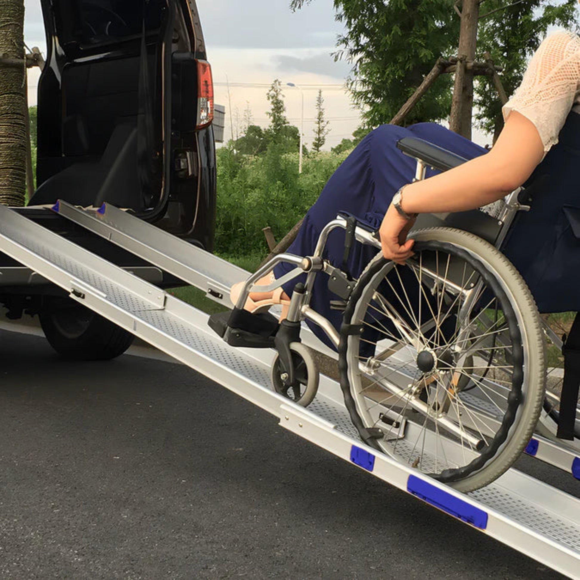 Person using a wheelchair being loaded onto a vehicle with a ramp